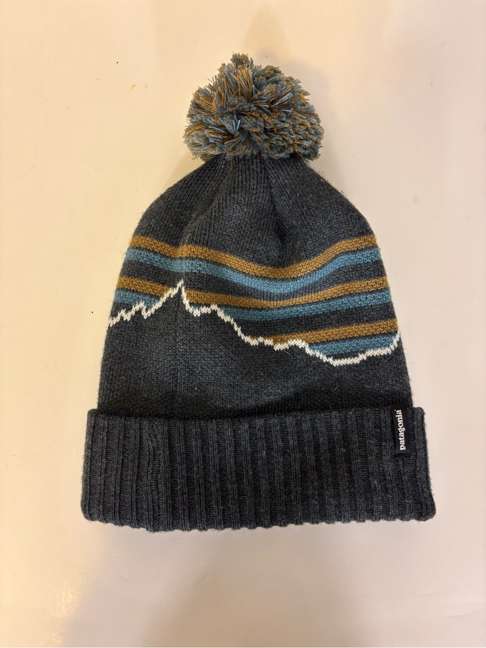 Patagonia Unisex Charcoal Beanie with Blue and Gold Stripes and Pom Winter Hat